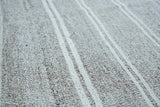 Close-up of hand woven flatweave with speckled salt and pepper ground and light beige stripes.