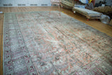 Vintage Tabriz carpet detail: Distressed blush red field, earthen green motifs, exposed foundation.
