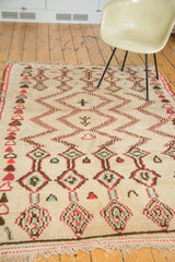 Plush ivory pile of the vintage Moroccan rug features geometric zig zags in brick red, mint green, and brown.
