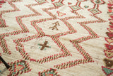 Plush ivory pile of the Moroccan rug with geometric zigzags, brick red and green motifs.