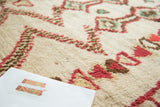 Plush ivory pile of the hand-knotted Moroccan rug with brick red geometric patterns.
