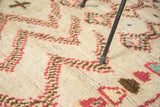 Plush hand-knotted pile featuring ivory, brick red, brown, and green geometric motifs.