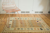 Vintage Kilim rug's geometric border and diamond field pattern in pastel earth tones.