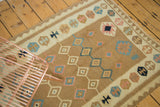 Vintage Kilim rug's geometric diamond patterns and border motifs in pastel earth tones.