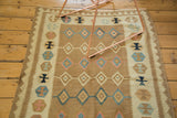 Linear rows of geometric diamonds in soft bronze, mint green, aqua, and ivory on the Kilim.