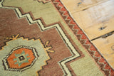 Vintage Oushak rug's floral end border and stepped geometric pattern in bronze, green, and brick red.