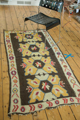 Distressed vintage Turkish Kilim runner featuring geometric medallions, brown, yellow, blue.