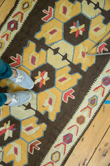 Distressed Kilim runner's bold geometric design in dark brown, sunflower yellow, and red accents.