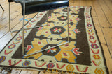 Distressed Kilim runner's yellow geometric medallions, ivory border, and fringed end.