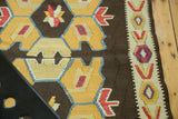 Hand-woven vintage Kilim runner detail: geometric border with bold red, yellow, blue, and purple motifs.