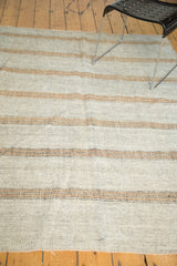 Textured detail of hand-woven kilim rug with light grey and bronze stripes.