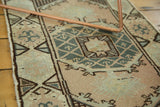 Textured corner of vintage Oushak runner with faded peach and green geometric patterns.