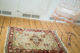 Distressed Oushak rug showing muted sea foam field and faded red floral border.