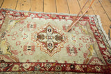 Faded sea foam Oushak rug corner showing distressed field, dark red border, and stylized florals.