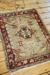 Distressed pile, faded sea foam field, and dark red floral border of this vintage Oushak rug.