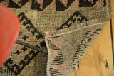 Vintage Turkish Oushak rug: hand-knotted black, sandy beige, faded peach geometric pattern, with exposed foundation.