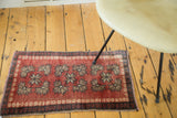 Vintage Oushak mat in cherry red with organized rows of geometric floral motifs.