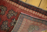 Folded corner of vintage Oushak rug showing cherry red geometric floral motifs and hand-knotted back.