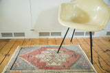 Vintage Oushak rug mat corner, with faded cinnabar red geometric stylizations.
