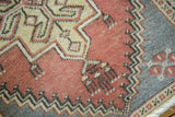 Vintage Oushak rug detail: faded cinnabar field, ivory stepped design, charcoal zig-zag border.