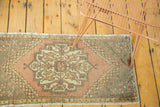 Distressed vintage Oushak rug: hexagonal medallion, peach, ivory, grey floral motifs.