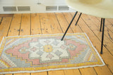 Vintage Oushak rug corner, pastel pink, grey, and yellow stepped diamond motif.