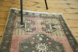 Distressed blush vintage Oushak rug with dark moss grey stepped medallion and floral motifs.