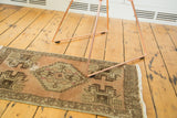 Vintage Oushak runner with stepped medallion, soft earth tones, and localized distress.