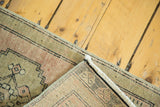 Vintage Oushak rug corner showing faded sage, peach pile and intricate hand-knotted foundation.