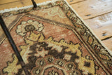 Distressed pile of a vintage Oushak rug with faded brick red and saffron gold.