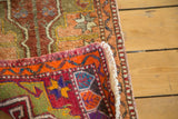 Vintage Oushak rug's rolled end with cream fringe and vibrant geometric red, orange, blue patterns.