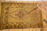 Vintage Oushak rug's lower right: speckled gold field, floral border, brick red motifs, fringe.