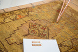 Diamond medallion with floral motifs and speckled gold field on vintage Oushak rug.