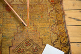 Vintage Oushak rug with gold speckled field, brick red lozenge motif, and floral border.