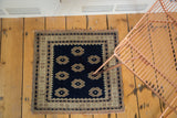 Vintage Oushak rug corner: dark navy field, simplistic floral motifs, and patterned border.