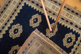Oushak rug corner revealing tightly woven foundation, beige fringe, and dark navy floral pattern.