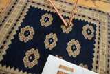 Vintage Oushak rug corner showing dark navy field with stylized floral motifs and beige border.