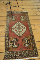 Vintage Oushak runner's bottom corner, faded brick red field, gold splayed floral motif, detailed border.