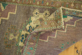 Folded corner of vintage Oushak rug, showing mauve, ivory, mint green, and aqua motifs.