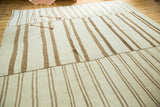 Textured view of vintage Kilim with ivory and bronze stripes, highlighting stitched panel join.