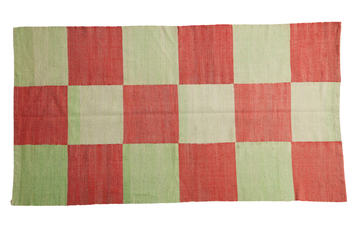 Hand woven Indo Patchwork rug with mint green and cinnabar red checkered blocks.