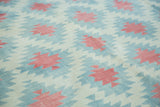 Hand woven Dhurrie rug featuring geometric diamonds in celadon green, red, and ivory.