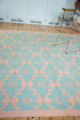 Hand woven Dhurrie carpet displaying repeating aqua turquoise and blush rose floral lattice.
