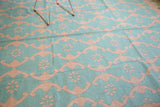 Close-up detail of the hand woven Indian Dhurrie carpet's aqua turquoise and blush rose floral lattice.