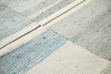 Modern hand woven rag rug close-up with simplistic ivory, denim blue, and charcoal stripes.