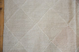 Hand woven texture with pale stone and blush lattice diamond patterns on a New Kilim carpet.