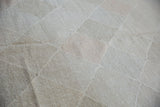Hand-woven new Kilim carpet detail, showing pale stone and blush geometric lattice design.