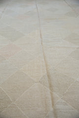 Geometric lattice diamond design of the hand woven Kilim carpet in pale stone, slate grey, and blush.