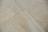 Texture of a pale stone hand-woven Kilim carpet with a natural fold.