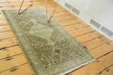 Distressed vintage Sivas rug corner with seafoam green border and intricate field patterns.